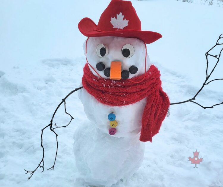 A backyard built Snowman with a red canadian cowboy hat and matching red scarf 