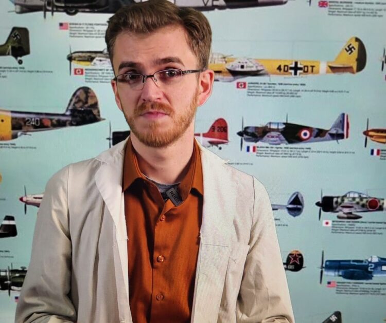 Image of Daniel Allers standing in front of a green screen with images of historical airplanes.