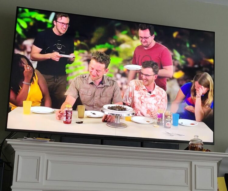Image of the History Plus Online team sitting at a table laughing at the reaction of one of them while eating scorpion.